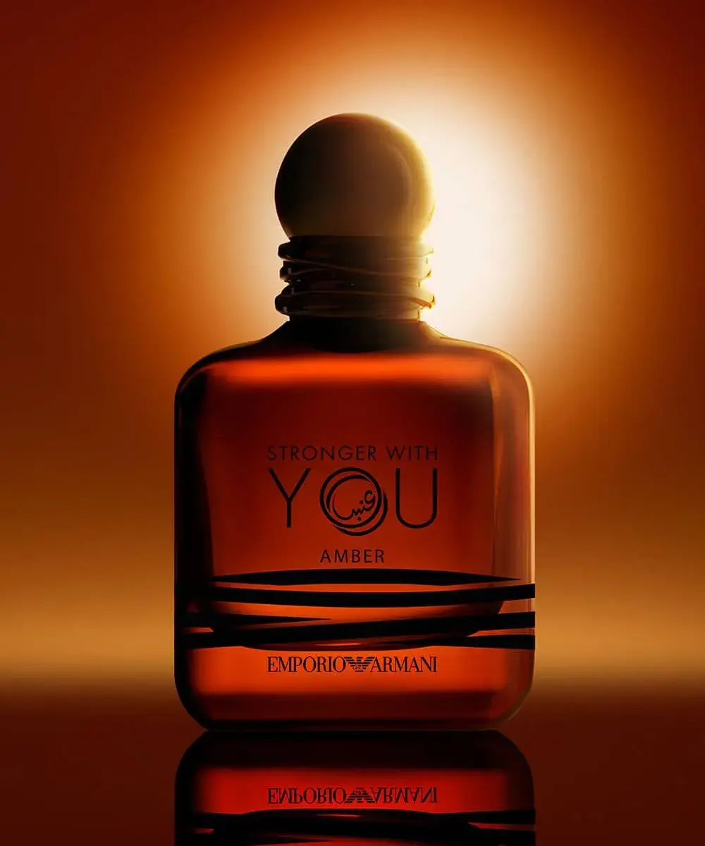emporio armani stronger with you amber 100ml candlelit backlit bottle بطری عطر استرانگر ویت یو آمبر آرمانی در نوری گرم و کهربایی، مانند شعلهی شمع در شبی سرد