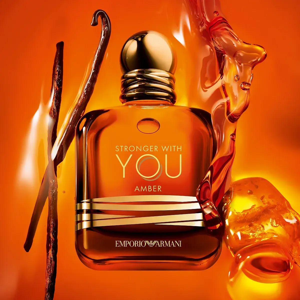 emporio armani stronger with you amber 100ml vanilla amber splash شیشهی کهربایی عطر جورجیو آرمانی استرانگر ویت یو آمبر میان موجی گرم و طلایی، کنار غلاف وانیل و تکههای رزین کهربایی