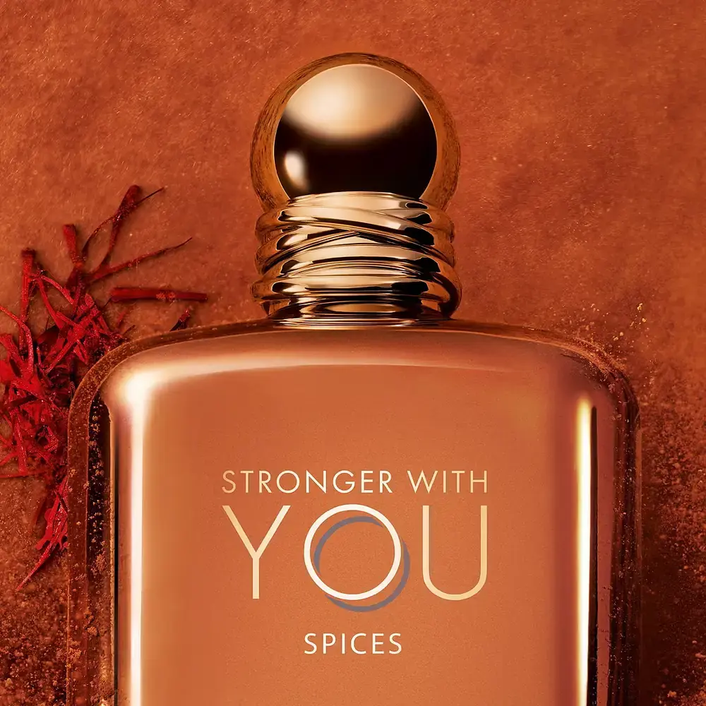 emporio armani stronger with you spices 100ml saffron cap close up نمای نزدیک بطری فلزی استرانگر ویت یو اسپایسز با درپوش طلایی، کنار رشتههای زعفران و پودر ادویه